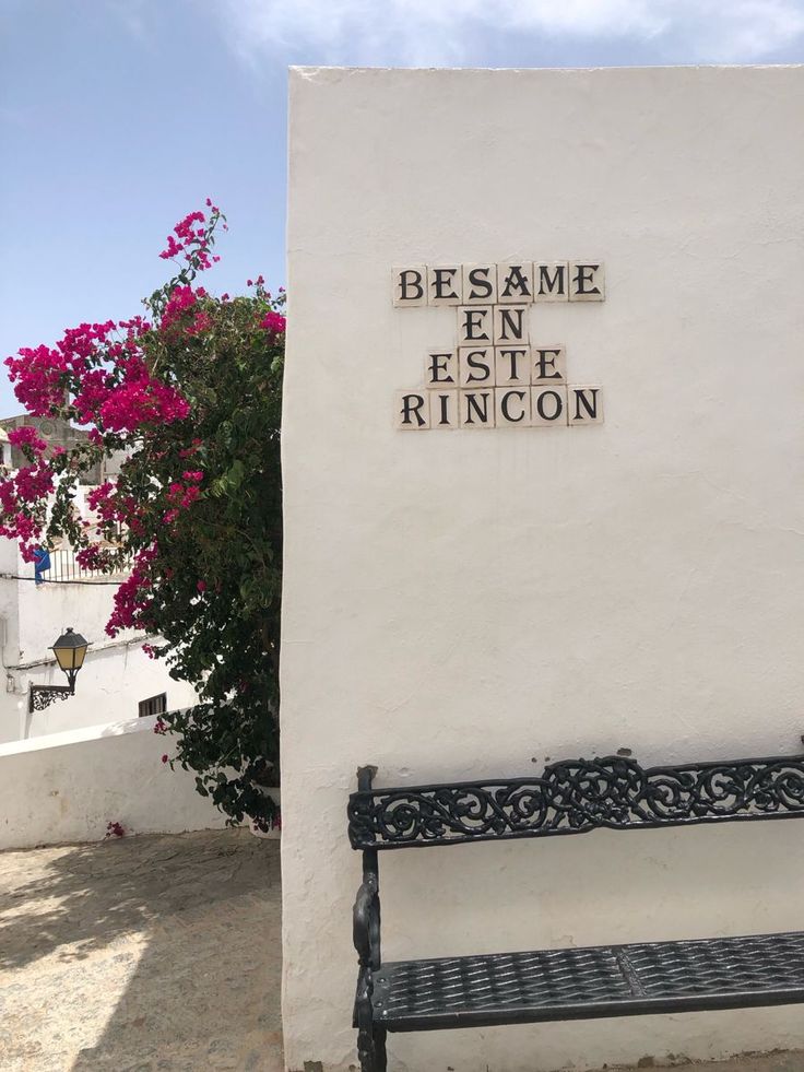 Spanish white wall with bougainvillea and a village bench